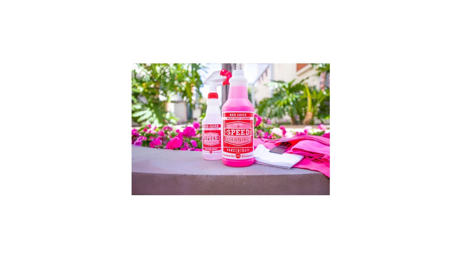 Red Juice cleaner bottle on a kitchen counter with plants in the background, designed for removing grease and buildup