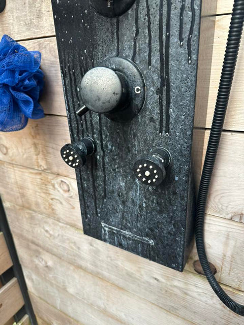 Black shower panel crusted with white mineral deposits