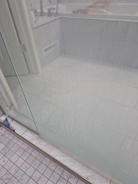 Glass shower door clouded with hard-water buildup