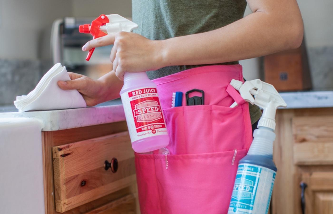 Professional Cleaner using Red Juice to clean a counter, wearing a Speed Cleaning apron